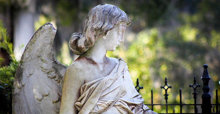Statue of angel at cemetery gravestone